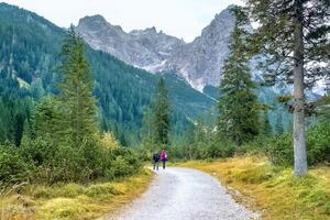 excursionismo viaje, dolomitas paisaje. par de turistas es caminando a lo largo un amplio sendero en el dolomitas. el tofane grupo en el dolomitas, Italia, Europa. foto