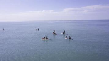 Group of people swim on SUP Board. Clip. Beautiful seascape with people resting on water with SUP boards. Top view of turquoise sea with people on swimming boards photo