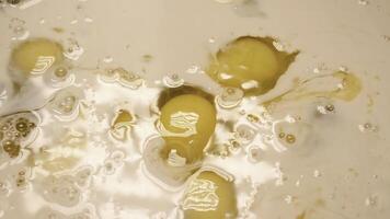 Close-up of raw eggs in liquid. Stock footage. Raw eggs spread in dough liquid. Preparation of dough for baking with raw eggs and mixed liquid photo