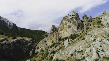 Top view of rock ridges on the background of green mountains and blue sky. Shot. Beautiful mountain landscape with rock massifs and green grass on background of sky photo