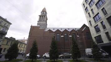 Exterior architecture of Catholic Church is made of dark brick. Action. Ancient architecture of Catholic Church with bell tower in center of city. Our lady of Lourdes Roman Catholic Church photo