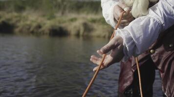 Ancient fishing technique, fisherman in old fashioned costume getting a fishing net. Stock. Man in old clothes of rococo manner pulling a fishing net, standing in the river in a sunny day. photo