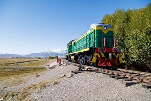 green diesel locomotive crossing small bridge at summer day in Balykchy, Kyrgyzstan photo