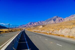empty highway road with separating concrete barrier in mountains at sunny autumn day photo