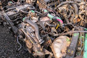 many used internal combustion engines on the ground of junkyard at cloudy day photo