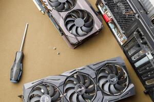 graphics card upgrading concept, two gaming graphics cards near desktop miditower ATX pc case on tan fabric background photo