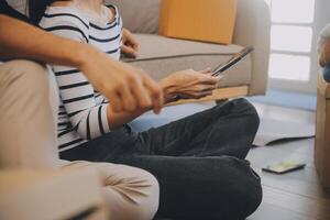 Two Asian blogger showing clothes in front of the camera to recording vlog video live streaming at her shop. Online Shopping Cart notion. on sofa at home photo