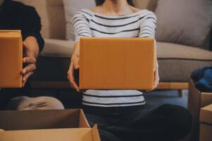 Two Asian blogger showing clothes in front of the camera to recording vlog video live streaming at her shop. Online Shopping Cart notion. on sofa at home photo
