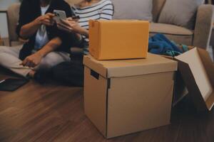 Two Asian blogger showing clothes in front of the camera to recording vlog video live streaming at her shop. Online Shopping Cart notion. on sofa at home photo