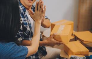 Two Asian blogger showing clothes in front of the camera to recording vlog video live streaming at her shop. Online Shopping Cart notion. on sofa at home photo