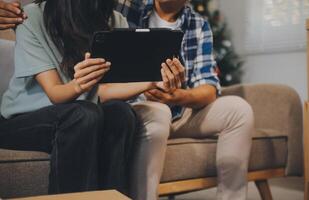 Two Asian blogger showing clothes in front of the camera to recording vlog video live streaming at her shop. Online Shopping Cart notion. on sofa at home photo