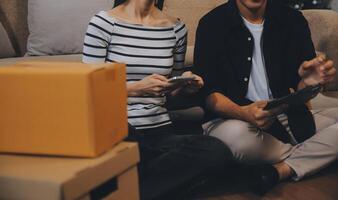 Two Asian blogger showing clothes in front of the camera to recording vlog video live streaming at her shop. Online Shopping Cart notion. on sofa at home photo