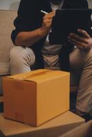 Two Asian blogger showing clothes in front of the camera to recording vlog video live streaming at her shop. Online Shopping Cart notion. on sofa at home photo