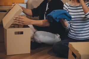 Two Asian blogger showing clothes in front of the camera to recording vlog video live streaming at her shop. Online Shopping Cart notion. on sofa at home photo