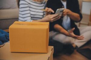 Two Asian blogger showing clothes in front of the camera to recording vlog video live streaming at her shop. Online Shopping Cart notion. on sofa at home photo