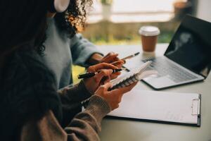 asiático mujer de negocios trabajando en ordenador portátil computadora Mira para trabajo en línea, Lanza libre mirando y mecanografía en cuaderno en mesa, estilo de vida de mujer estudiando en línea foto