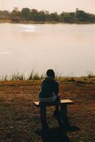 Silhouette of young man sits praying alone at the top of the mountain at sunset with beautiful natural sunlight. photo