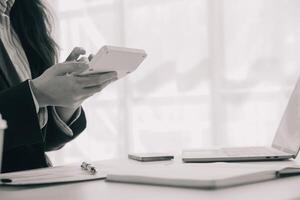 Businessman using a calculator to calculate numbers on a company's financial documents, he is analyzing historical financial data to plan how to grow the company. Financial concept. photo