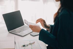 Businessman using a calculator to calculate numbers on a company's financial documents, he is analyzing historical financial data to plan how to grow the company. Financial concept. photo