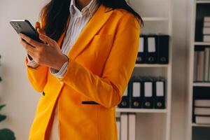 Young smiling business woman using smartphone near computer in office, copy space photo