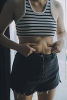 mujer cuerpo grasa barriga. obeso mujer mano participación excesivo barriga gordo. dieta estilo de vida concepto a reducir barriga y forma arriba sano estómago músculo. foto