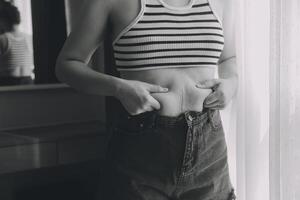 mujer cuerpo grasa barriga. obeso mujer mano participación excesivo barriga gordo. dieta estilo de vida concepto a reducir barriga y forma arriba sano estómago músculo. foto