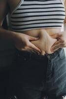 mujer cuerpo grasa barriga. obeso mujer mano participación excesivo barriga gordo. dieta estilo de vida concepto a reducir barriga y forma arriba sano estómago músculo. foto