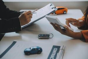 Closeup asian male people car salesman or sales manager offers to sell a car and explains and reads the terms of signing a car contract and insurance. photo