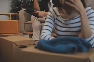 Two Asian blogger showing clothes in front of the camera to recording vlog video live streaming at her shop. Online Shopping Cart notion. on sofa at home photo