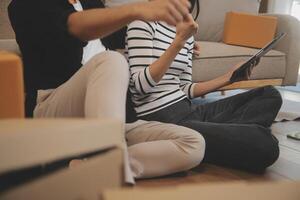 Two Asian blogger showing clothes in front of the camera to recording vlog video live streaming at her shop. Online Shopping Cart notion. on sofa at home photo