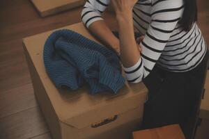 Two Asian blogger showing clothes in front of the camera to recording vlog video live streaming at her shop. Online Shopping Cart notion. on sofa at home photo