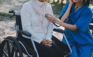 nurse with elderly man in wheelchair at park photo