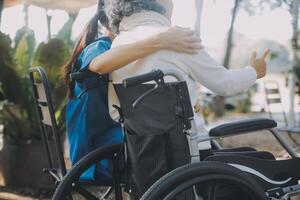 A nurse take care a senior male on wheelchair in his garden at home photo