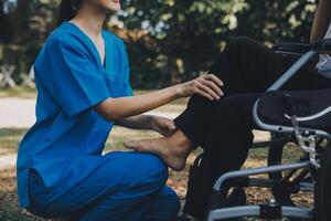 young asian physical therapist working with senior woman on walking with a walker photo