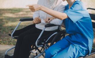 A nurse take care a senior male on wheelchair in his garden at home photo