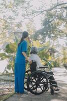 A nurse take care a senior male on wheelchair in his garden at home photo