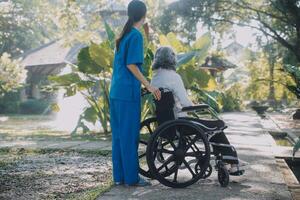 un enfermero tomar cuidado un mayor masculino en silla de ruedas en su jardín a hogar foto