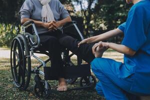 young asian physical therapist working with senior woman on walking with a walker photo