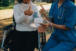 nurse with elderly man in wheelchair at park photo