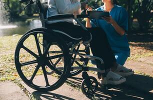 enfermería personal hablando a un mayor persona sentado en un silla de ruedas. foto