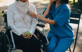 nurse with elderly man in wheelchair at park photo