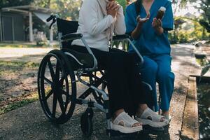 nurse with elderly man in wheelchair at park photo