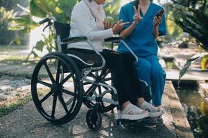 nurse with elderly man in wheelchair at park photo