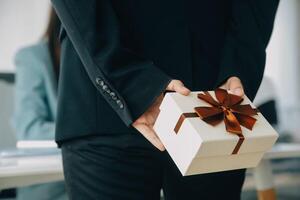 Young businessman giving his colleague present in office. Young man surprise beautiful businesswoman in office. photo