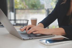 Asian Businesswoman Using laptop computer and working at office with calculator document on desk, doing planning analyzing the financial report, business plan investment, finance analysis concept. photo