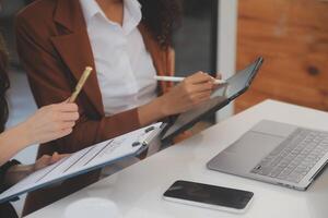 Asian Businesswoman Using laptop computer and working at office with calculator document on desk, doing planning analyzing the financial report, business plan investment, finance analysis concept. photo