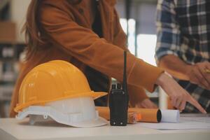 masculino y hembra industrial ingenieros en difícil sombreros discutir nuevo proyecto mientras utilizando ordenador portátil. ellos hacer demostración gestos ellos trabajo en un pesado industria fabricación fábrica. foto