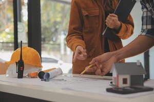 masculino y hembra industrial ingenieros en difícil sombreros discutir nuevo proyecto mientras utilizando ordenador portátil. ellos hacer demostración gestos ellos trabajo en un pesado industria fabricación fábrica. foto