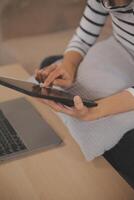 Young attractive asian woman resting using browsing tablet computer on sofa at home, happy girl sitting on couch relax reading digital gadget with excited, communication and lifestyle concept. photo