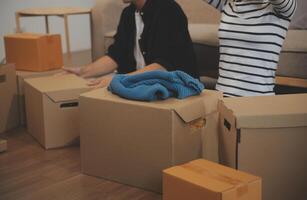 Two Asian blogger showing clothes in front of the camera to recording vlog video live streaming at her shop. Online Shopping Cart notion. on sofa at home photo